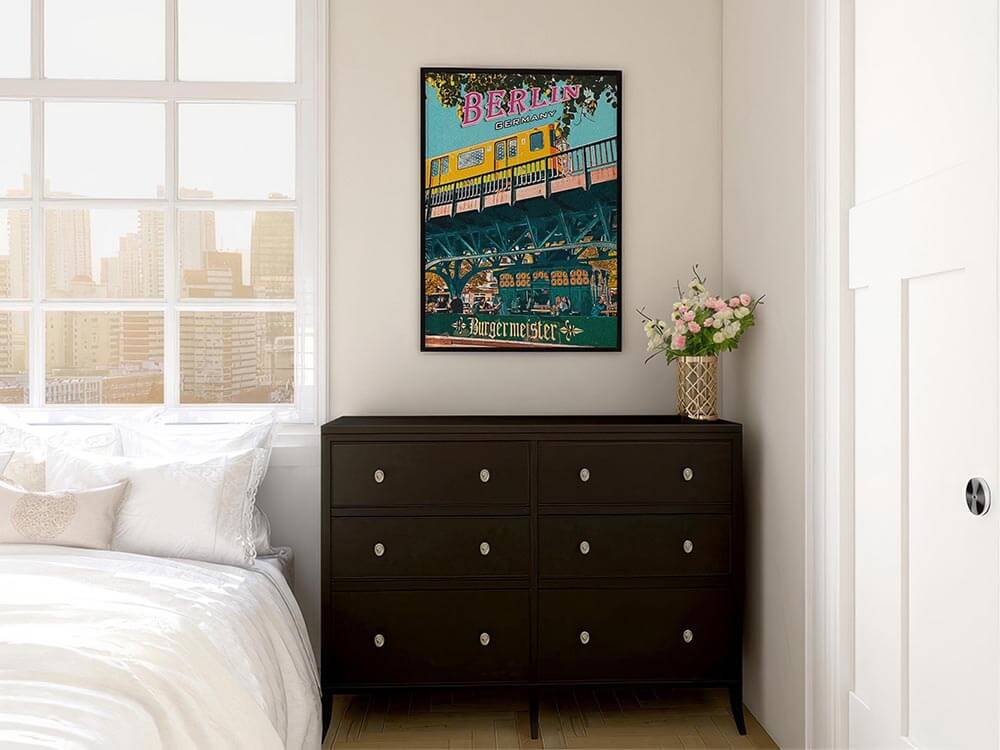 Vintage Berlin travel poster above a dark wood dresser in a bright white bedroom with roses